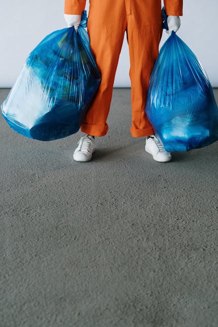A person vacuuming a patterned, area rug in a domestic setting with a yellow canister vacuum cleaner. The rug has a floral design with muted tones of green, beige, and orange, and covers a wooden floor. The individual is dressed casually in jeans, sneakers, and a beige jacket, and is using the vacuum's extension wand to clean the surface thoroughly. Bright, natural light illuminates the space, highlighting the clean and well-maintained appearance of the rug and floor. The scene reflects professional domestic cleaning practices, with meticulous attention to surface cleaning and hygiene, as emphasized by Carpet Cleaning Pimlico in their services for deep cleaning and sanitisation.